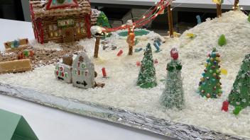 Ski slope scene including a lodge, frozen pond and campfire constructed from gingerbread and other sweets