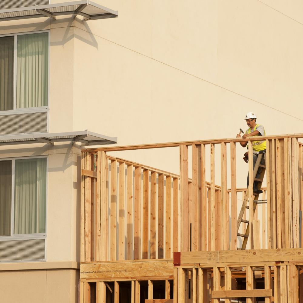 Construction worker hammers wooden beams for future hotel