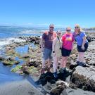 Eric O'Brien posing with family at a rocky beach shore.